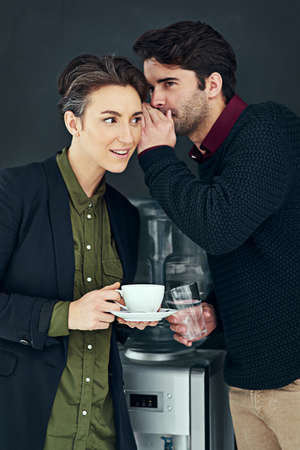 Coffee and gossip go together so well. Cropped shot of two colleagues gossiping by the water cooler...
