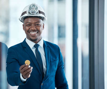 Whats mine can be yours. Shot of a young businessman holding a bitcoin in a modern office.の写真素材