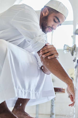 Cleanse the outside before the inside. Shot of a young man washing his hand in a mosque.