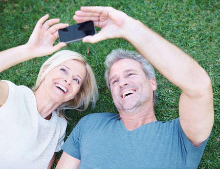 This is one for the album. A happy mature couple taking a picture of themselves with a smartphone.