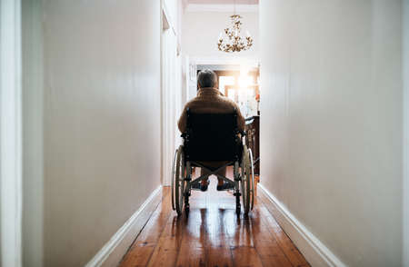 Let the promise of tomorrow keep you going. Rearview shot of a senior woman sitting in her wheelchair at home.の写真素材