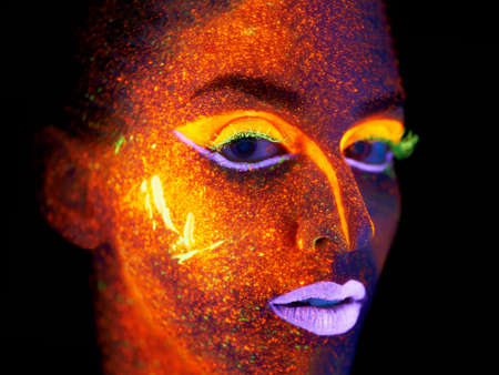 Ready for the nightlife. Portrait of a young woman with with neon paint on her face posing.の写真素材