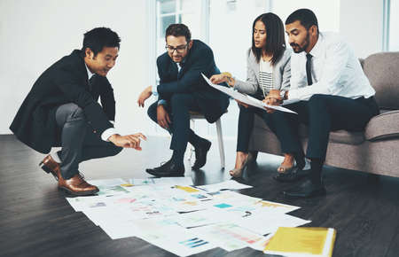 Success stems from good ideas. Shot of businesspeople having a brainstorming session with documents spread out in front of them.の写真素材