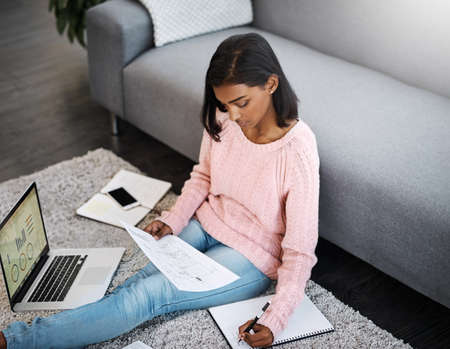 Getting work done in my spare time. Shot of a young beautiful woman using a laptop and going through...