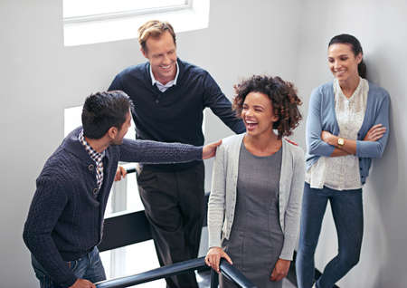 Impromptu congratulations. Shot of a group of office coworkers standing in a stairwell chatting.