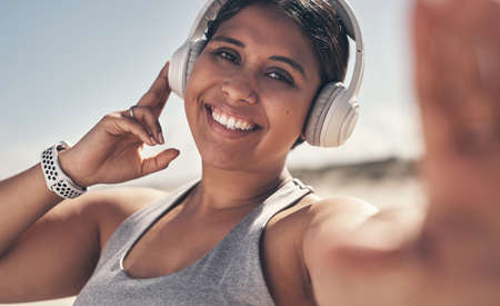 Exercise makes you feel good, the benefits are obvious. Shot of a young woman wearing headphones while out for a workout.の写真素材