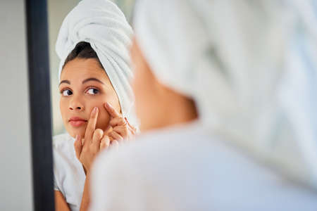 Popping them wont solve the problem. Shot of an attractive young woman squeezing a pimple on her...