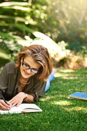 Putting it in her diary. Shot of an attractive young woman writing in her diary while outside on the...