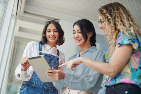 Evaluating trends and making relevant changes to suit their market. Shot of a group of businesswomen using a digital tablet together in an office.の写真素材