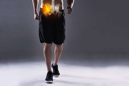 Carrying a hip injury. Cropped shot of a young man in the studio with cgi highlighting his hip...