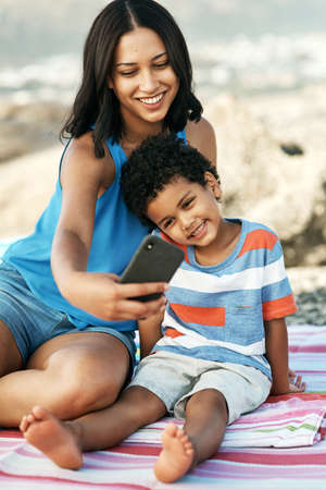 Making memories to last a lifetime. Shot of a mother and her son taking selfies at the beach.の写真素材
