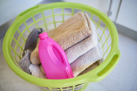 Keep your towels clean. Shot of a bottle of detergent and folded towels in a laundry basket.の写真素材