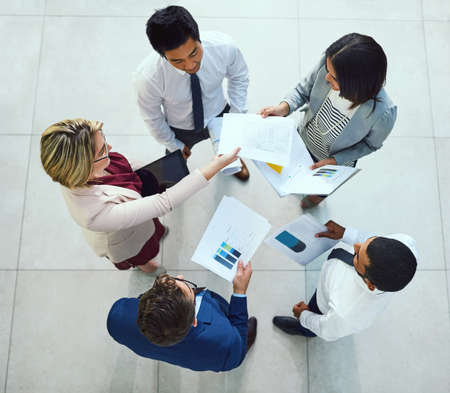 Analysing the latest reports together. High angle shot of a diverse group of businesspeople going...