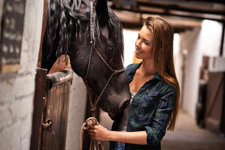 Hey girl, why. A young woman in a stable with her horse.