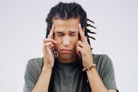 Whats the best cure for headaches guys. Shot of a young man holding his head while suffering from a...