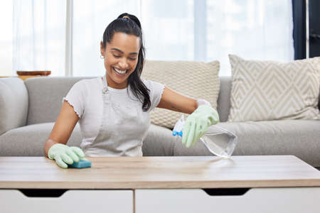 I never miss a spot. Shot of an attractive young woman using a sponge and spray bottle to clean the surfaces at home.の写真素材