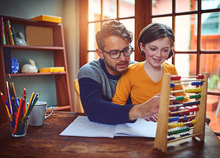 Let me show you another way to find the answer.... Shot of a father helping his little daughter with her homework.の写真素材