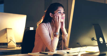 Shes trying hard to focus. Cropped shot of a beautiful young woman working at night in a modern office.の写真素材