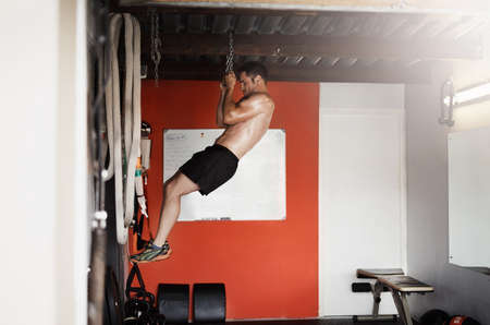 Never let go of your goals. Full length shot of a handsome and muscular young man doing pullups...