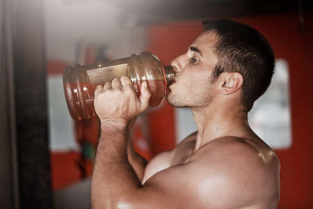 Getting started with a little pre workout. Cropped shot of a handsome and muscular young man...