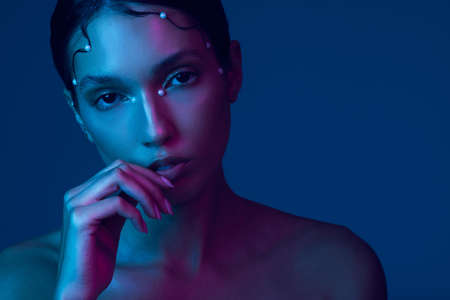 Georgeously glamorous. Cropped portrait of an attractive young woman posing in studio against a blue background.の写真素材