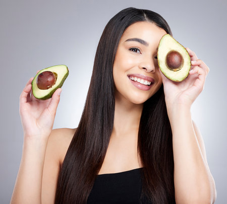 Going organic was a move in the ripe direction for me. Studio portrait of an attractive young woman posing with an avocado against a grey background.の写真素材