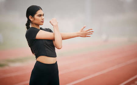 If youre confident, youll achieve anything you put your mind to. Shot of an athletic young woman stretching while out on the track.の写真素材