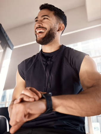 Doing his best as always. Shot of a sporty young man checking his watch while exercising in a gym.