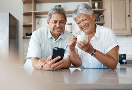 Theyve got the hang of technology. Shot of a senior couple using a phone together at home.の写真素材