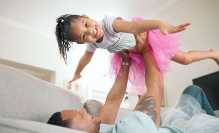 Look, Im a plane. Shot of an adorable little girl bonding with her father in the living room at home.の写真素材