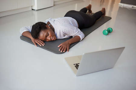 This workout really tires me out. Shot of a young woman looking exhausted while exercising at home.