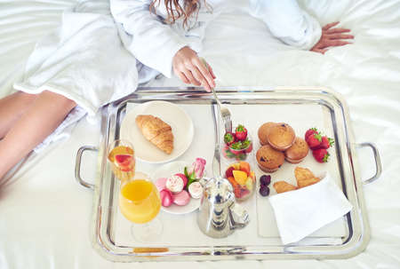 Start your morning off right. High angle shot of an unrecognizable woman enjoying a healthy breakfast on her hotel bed.の写真素材