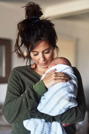 My precious little boy. Shot of a cheerful young woman holding her little infant son at home during...