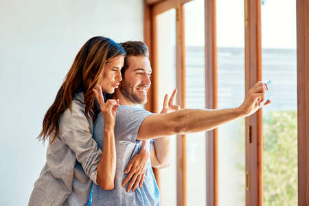 Its been one wacky day for us. Shot of a happy young couple taking a selfie together at home.