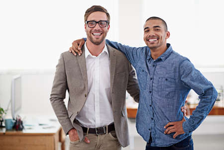 We get it done every time. Shot of two colleagues standing arm in arm in an office.の写真素材