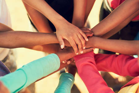 All for one. Cropped shot of a group of children standing with their hands in a huddle outside.