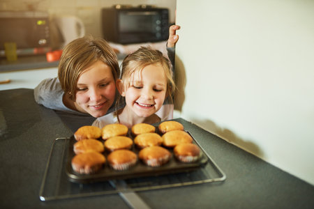 Homemade happiness. Cropped shot of two young siblings looking at some freshly baked cupcakes.の写真素材