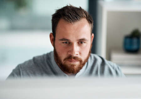 Set straight on finishing his tasks. Shot of a young businessman working on a computer in an office.