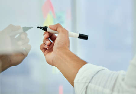 Drawing up his master plan. Cropped shot of an unrecognizable businessman working on a glass wipe...