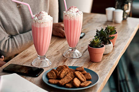 Out for some refreshments. Cropped shot of an unrecognizable woman having a milkshake and cookies...