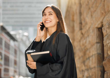 You miss 100 of the shots you dont take. Shot of a young female judge using her smartphone to make a call.の写真素材