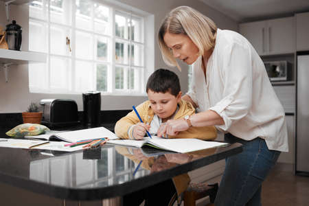 If you break it down its easier. Shot of a beautiful mother helping her son with his homework.の写真素材