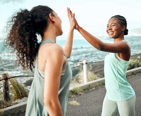 We reached another fitness goal. Shot of two young women giving each other a high five while working out in nature.の写真素材