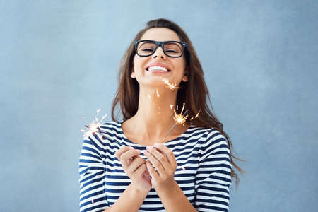 Everyday Im sparklin. Studio portrait of a beautiful young woman holding sparklers against a blue...