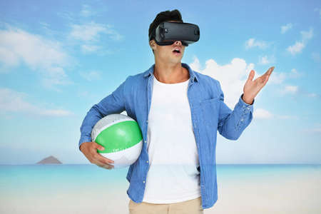 Its the getaway of my dreams. Shot of a young man wearing a VR headset superimposed over a beach landscape.の写真素材