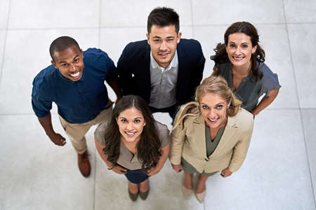 Our smiles were won through success. High angle portrait of a team of businesspeople posing together in their office.の写真素材