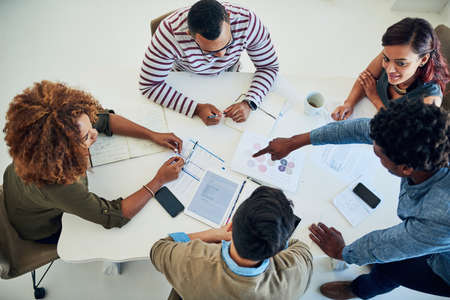 Sharing the workload is a sure way to success. Shot of a group of colleagues having a meeting in a...