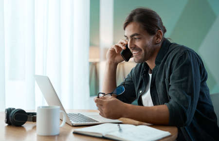 The only way to succeed is to work hard. Shot of a young man doing paperwork while using a laptop at...