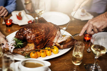 Whats your favourite piece. Cropped shot of an unrecognizable person cutting into a turkey at Christmas lunch.の写真素材