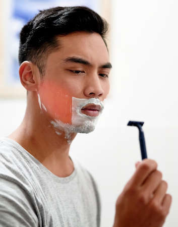 I really need to replace this. Shot of a young man at home getting razor burn on his face from shaving with a disposable razor.の写真素材